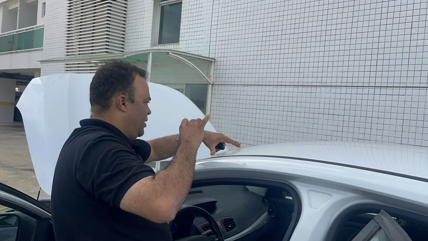 Edson aponta para o teto de um carro enquanto explica o que encontrou