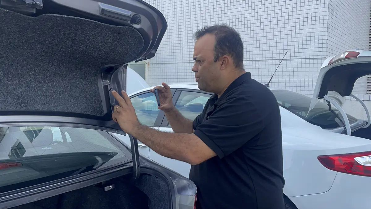 Edson Viana examina a dobradiça do porta-malas de um sedã